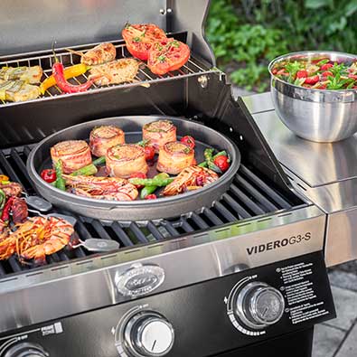 Lid of the Dutch oven in the Vario+ grill grate system with pieces of meat and asparagus on the Videro G3-S.