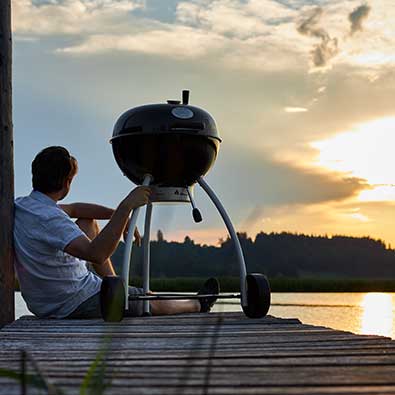 Holzkohle Kugelgrill auf Steg mit Sonnenuntergang