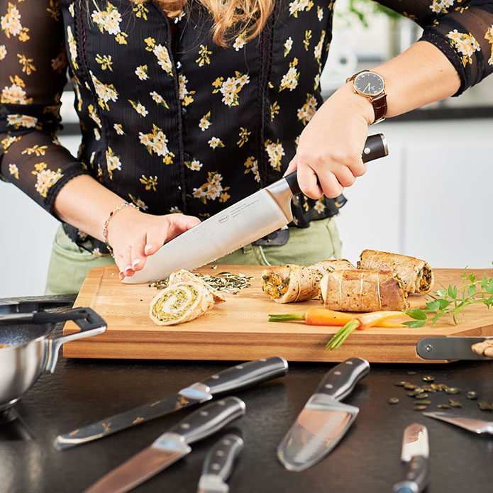Frau schneidet Kräuter mit Messer der Serie Artesano auf Schneidbrett