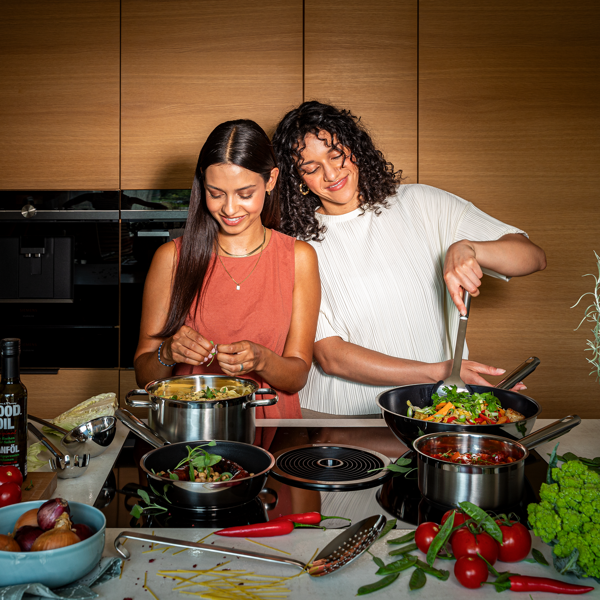 Zwei Frauen beim Kochen mit RÖSLE Töpfen Zwei Frauen kochen gemeinsam in einer modernen Küche mit Töpfen. Eine Frau bereitet Pasta...