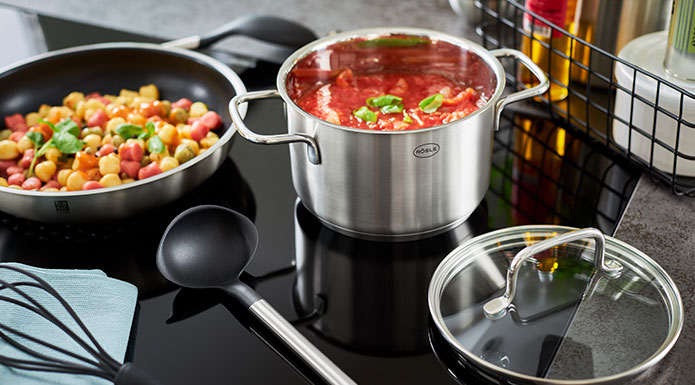 Cooking pot with tomato sauce and frying pan with gnocchi