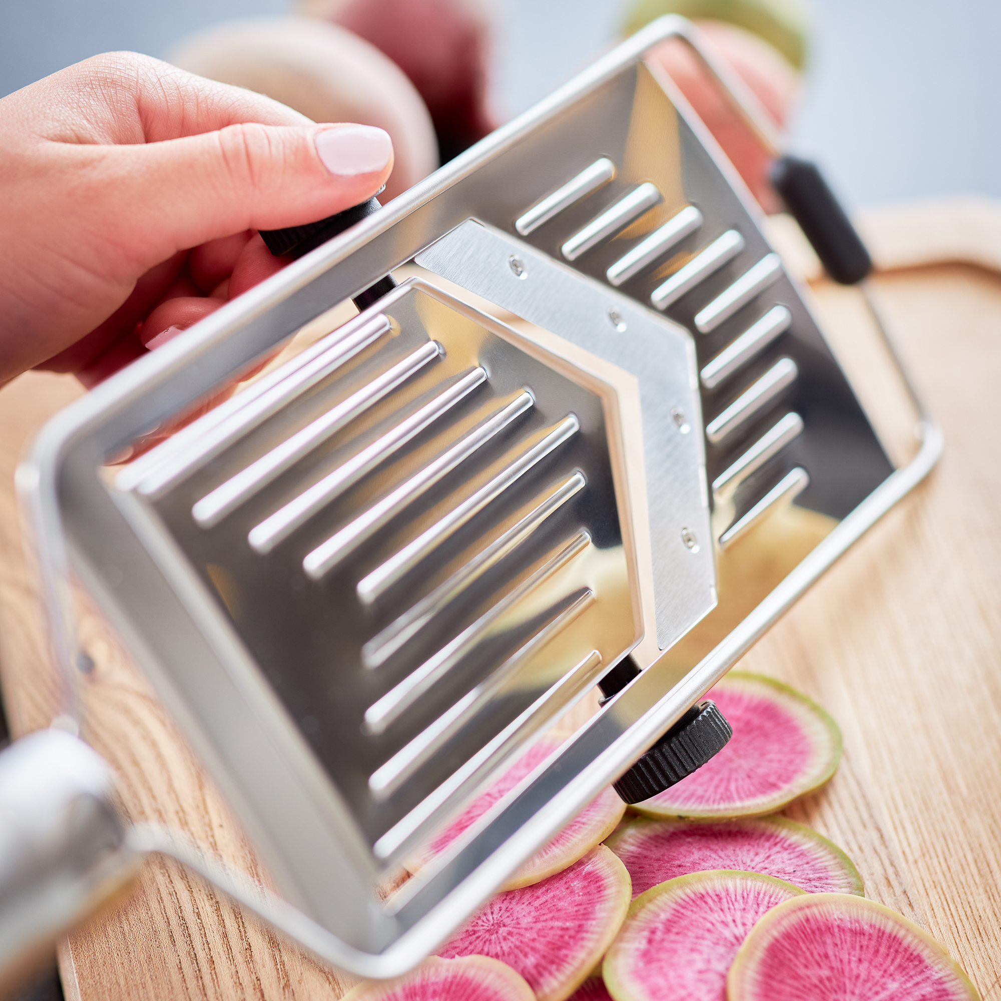 RÖSLE Edelstahl Hobel mit V-Klinge Hobel mit V-Klinge aus Edelstahl, in der Hand gehalten, auf einem Holzbrett mit geschnittenem...