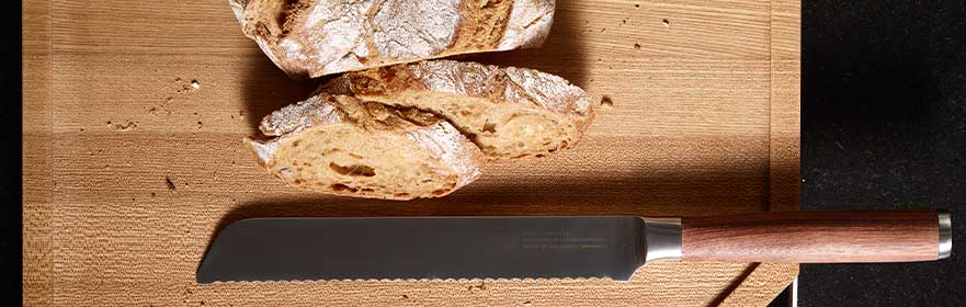 RÖSLE Brotmesser Masterclass Brotmesser der Masterclass-Serie mit gezahnter Klinge, neben geschnittenem Brot auf einem...