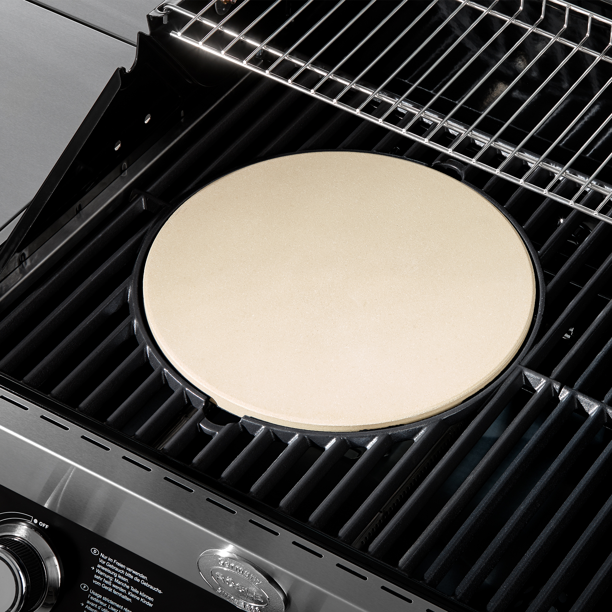 RÖSLE Pizzastein Vario auf Grill Pizzastein Vario, rund, 30 cm, beige, auf einem Grillrost platziert.