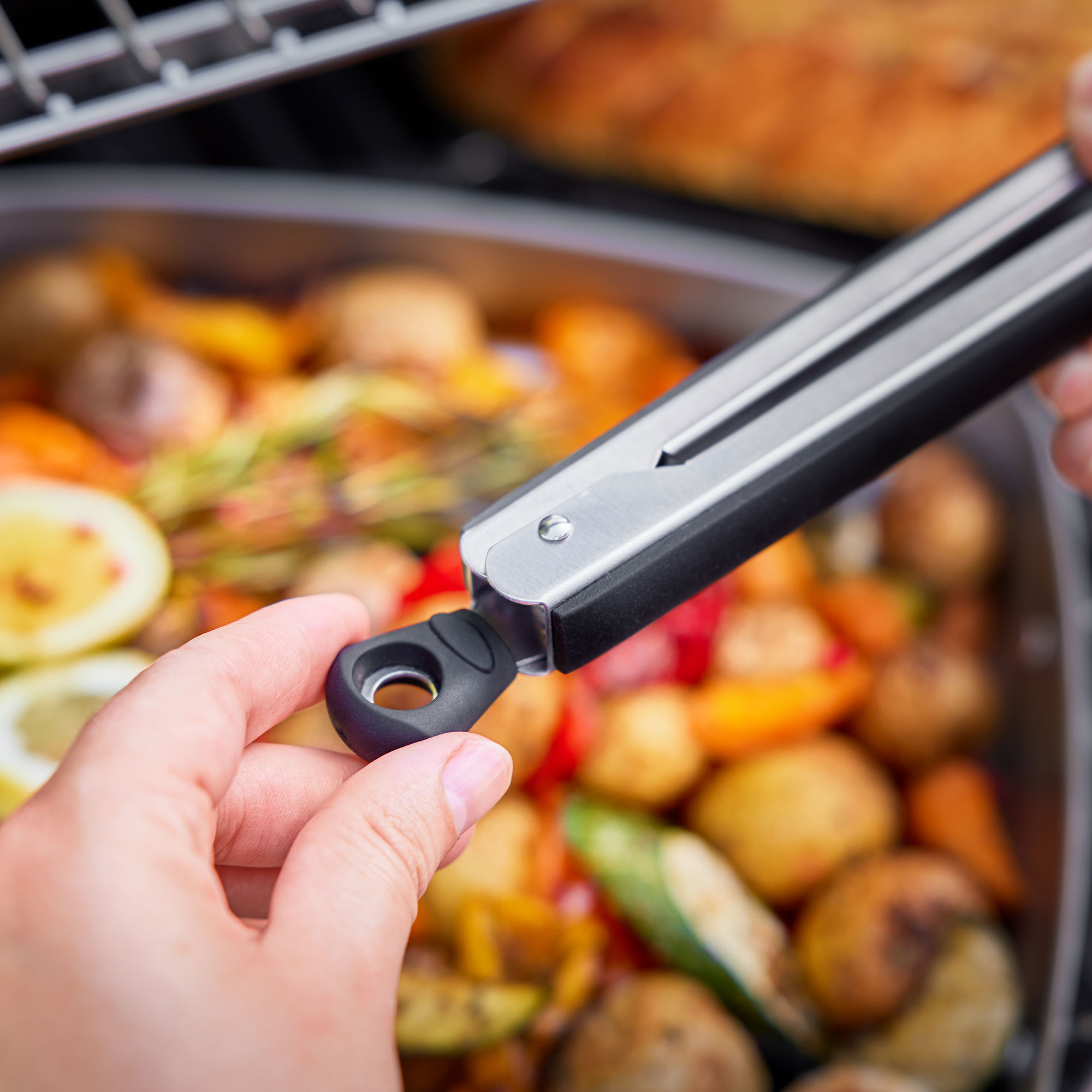 RÖSLE Grillzange in Aktion Grillzange aus Edelstahl, schwarz, wird zum Wenden von Grillgemüse verwendet.