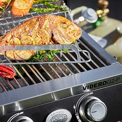 RÖSLE Gasgrill BBQ-Portable Videro G2-P Fischhalter mit gegrilltem Fisch auf Grillfläche des Videro G2-P
