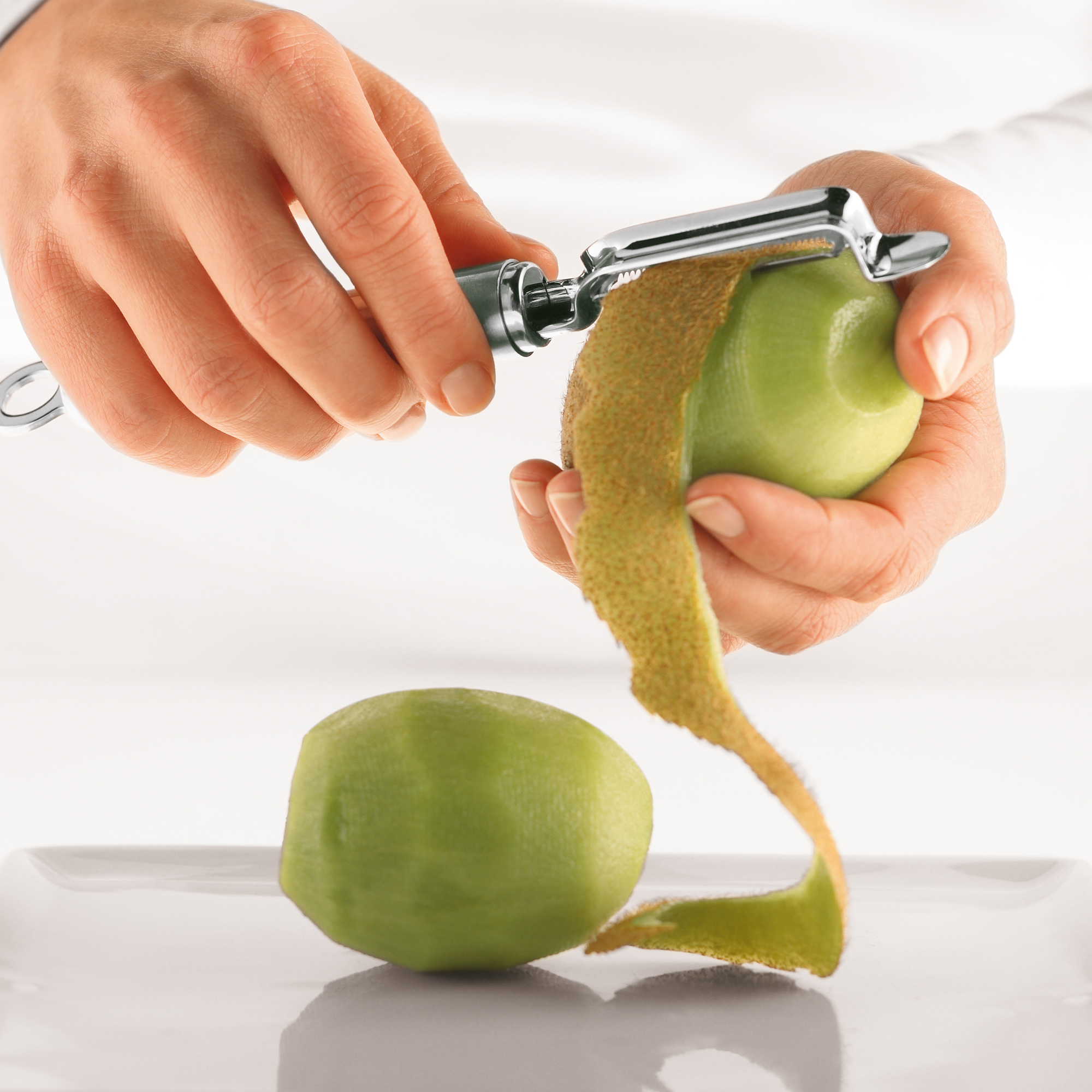 RÖSLE kiwi peeler with kiwi Kiwi peeler in action, peeling a green kiwi, peeling off the skin.