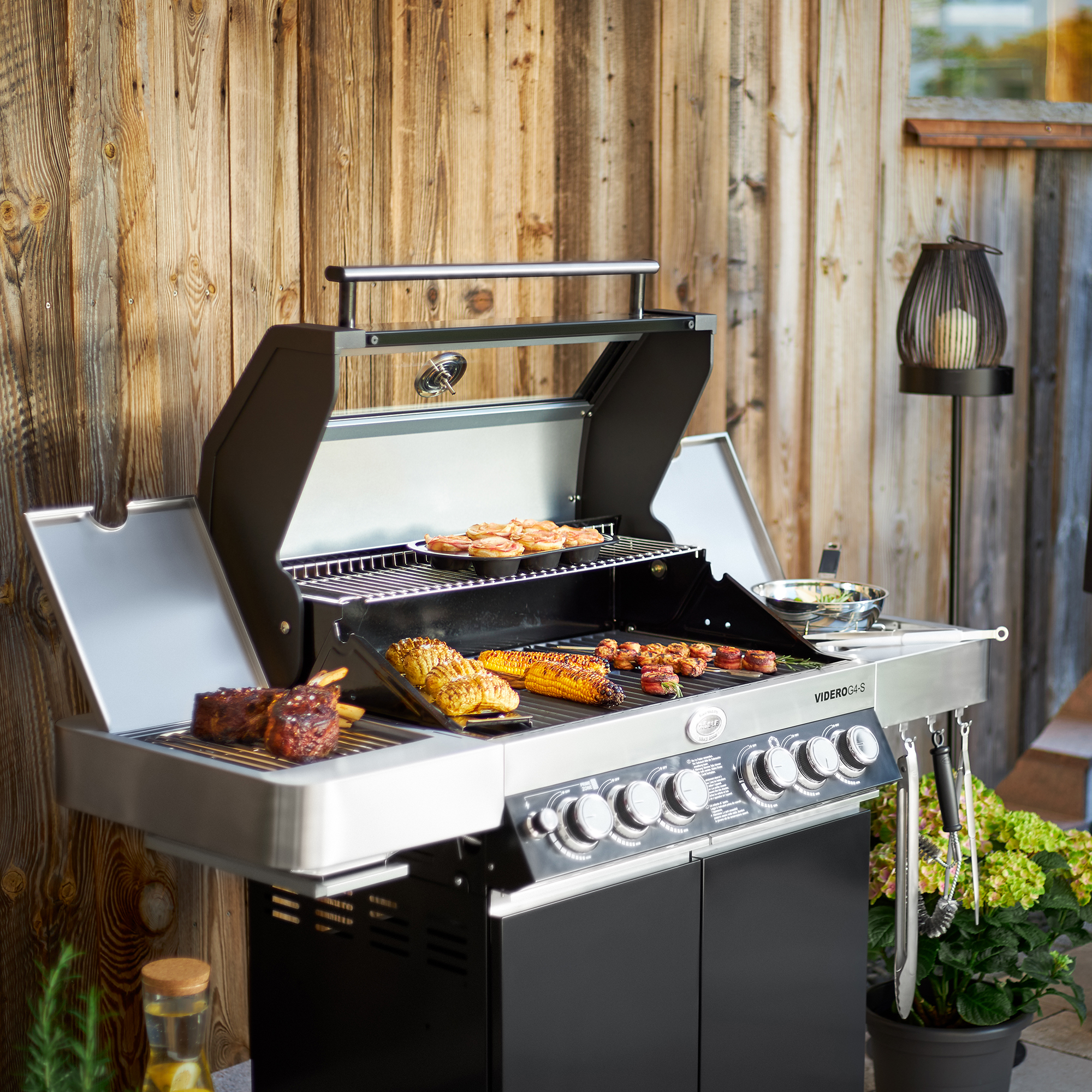 RÖSLE Gasgrill Videro G4-S Schwarz Gasgrill Videro G4-S in Schwarz mit Grillgut auf dem Rost und seitlicher Ablagefläche.