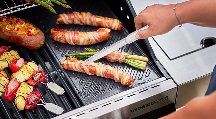 Asparagus wrapped with bacon is prepared on the grill plate