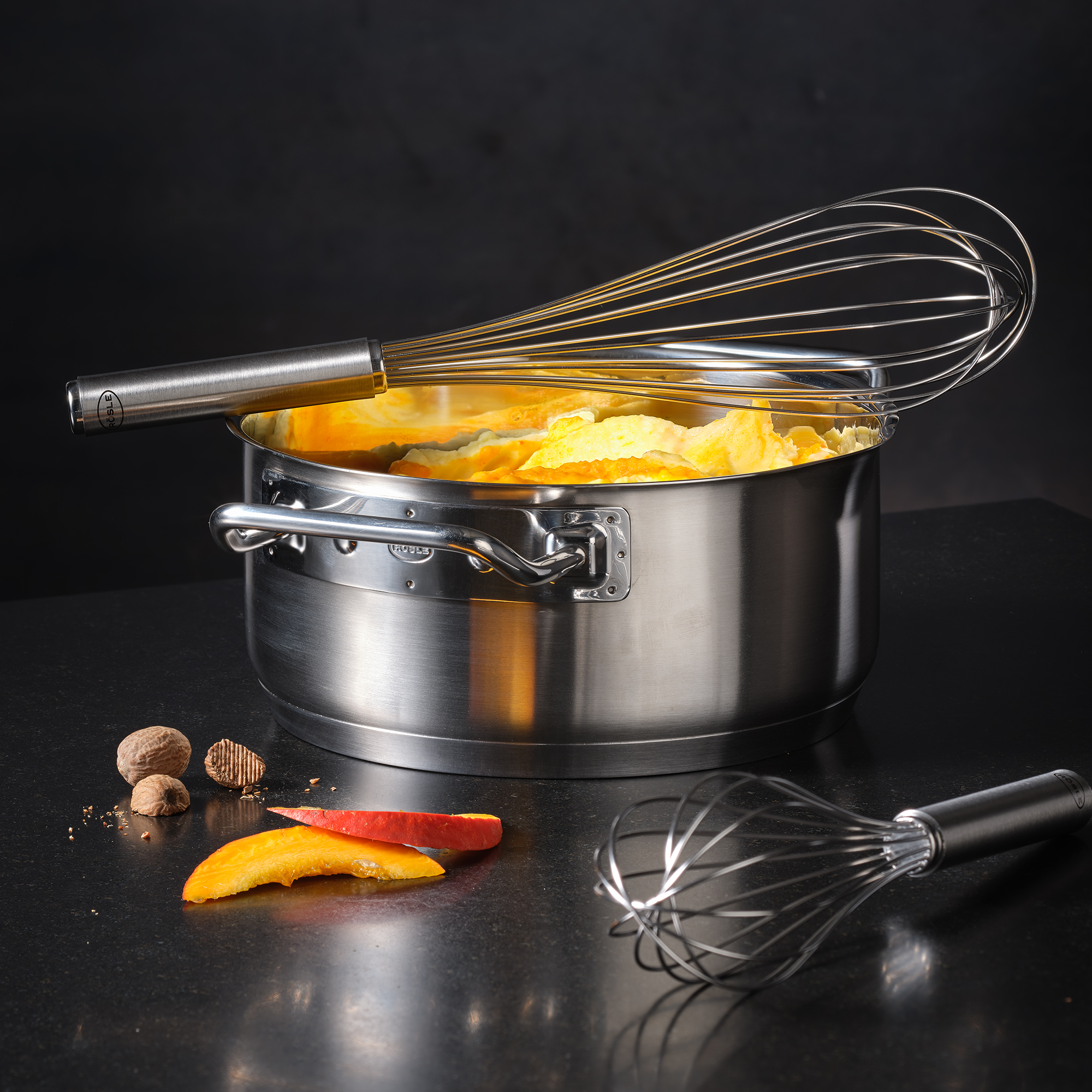 Bratentopf, 20 cm, aus Edelstahl, mit einem Schneebesen und Kürbisstücken im Topf.