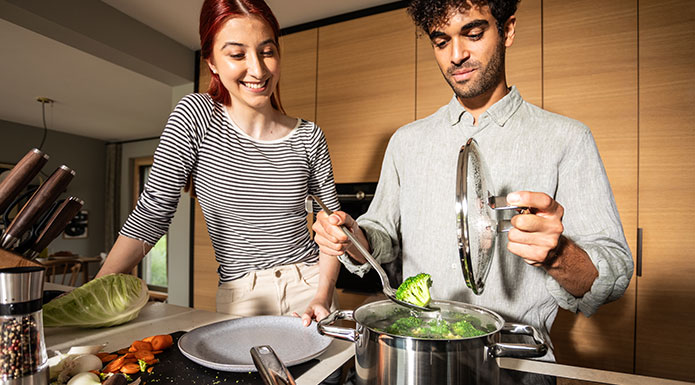 Hochwertige Töpfe Pärchen kocht zusammen Brokkoli in einem Topf