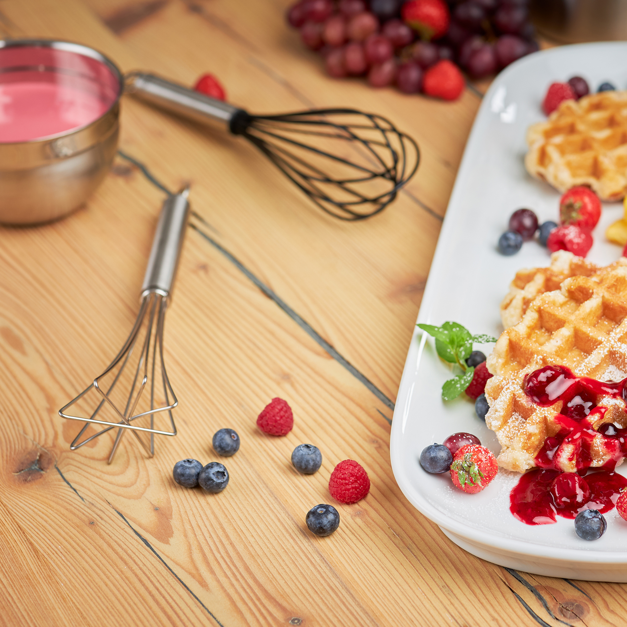 RÖSLE silicone whisk and waffles with berries Silicone whisk 27 cm near waffles with berries and sauce on a wooden tray.