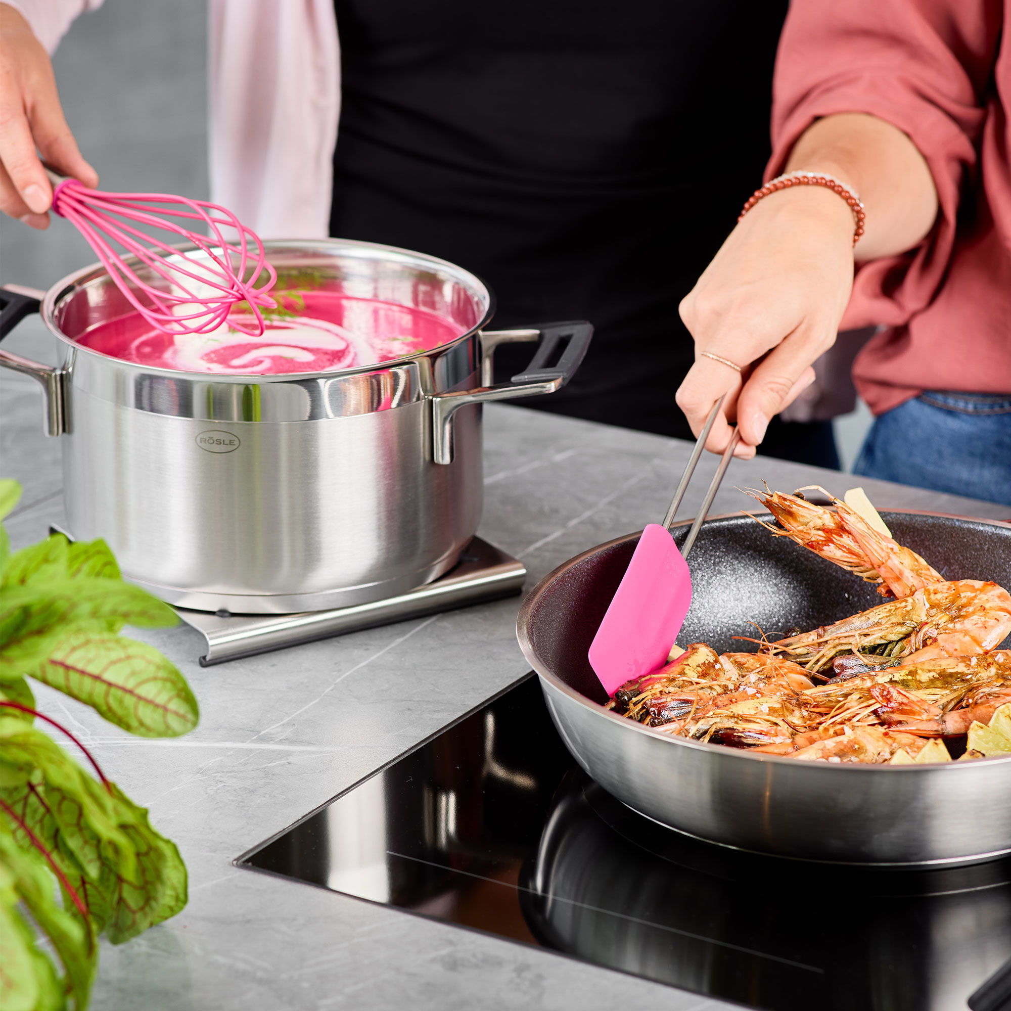 RÖSLE Teigschaber in Pink beim Kochen Teigschaber in Pink wird zum Wenden von Garnelen in einer Pfanne verwendet, während eine Person...