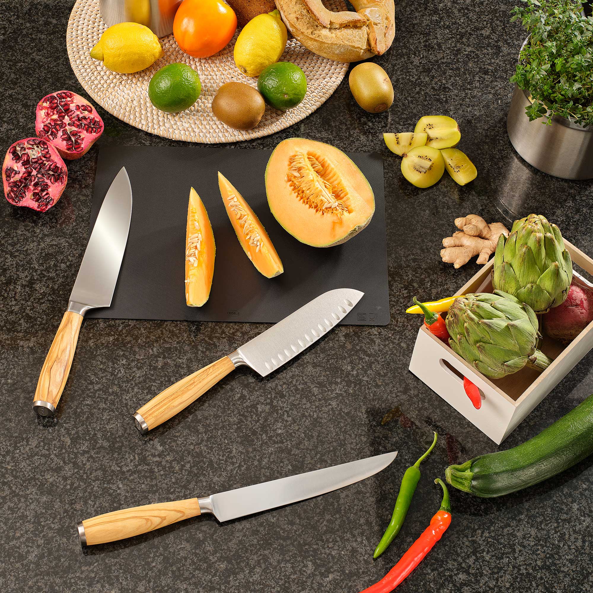 RÖSLE Fleischmesser und Kochmesser mit Obst und Gemüse Fleischmesser und Kochmesser auf einer Arbeitsfläche mit geschnittenem Obst und Gemüse.