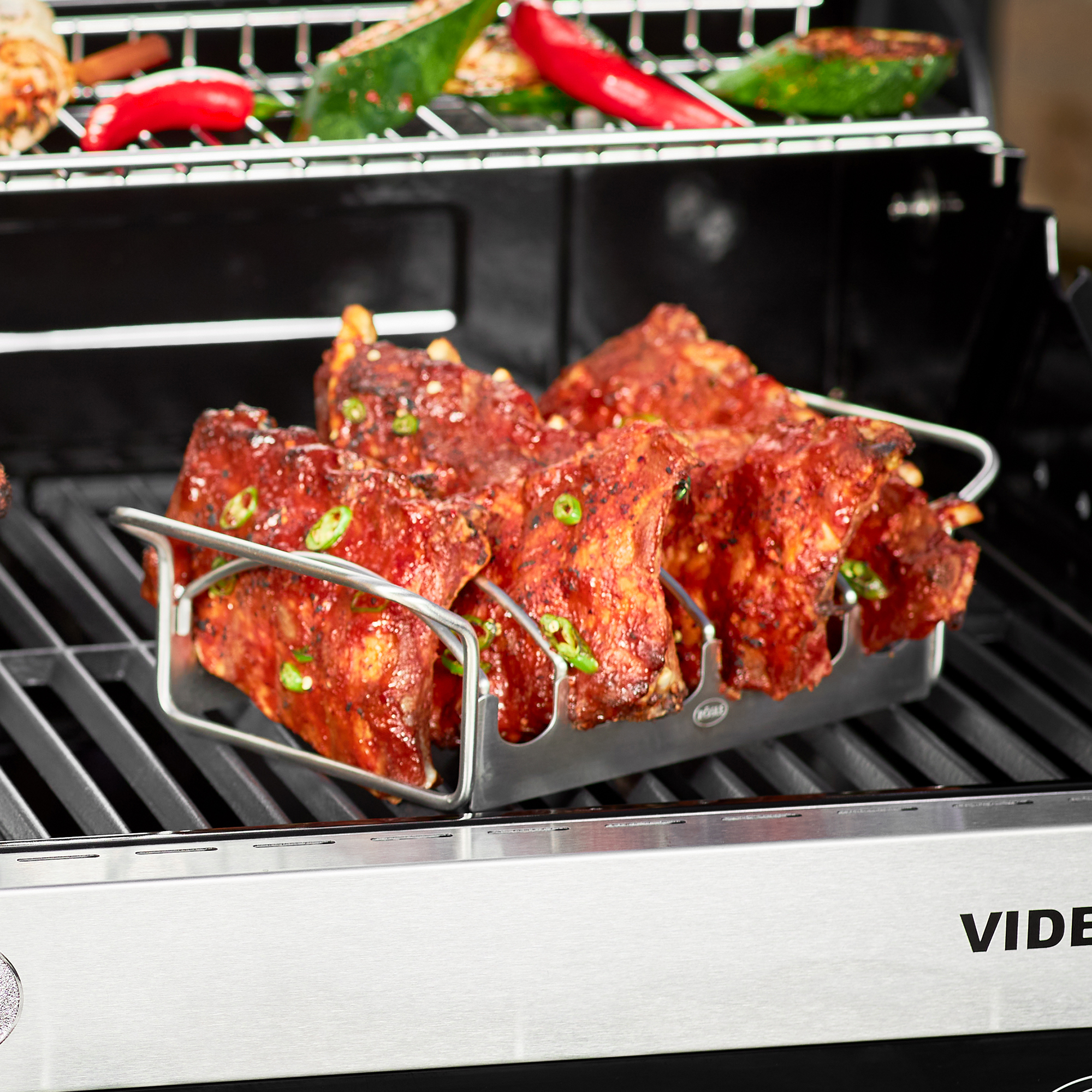 RÖSLE roast and rib holder with ribs Stainless steel roast and rib rack filled with marinated ribs on a grill rack.
