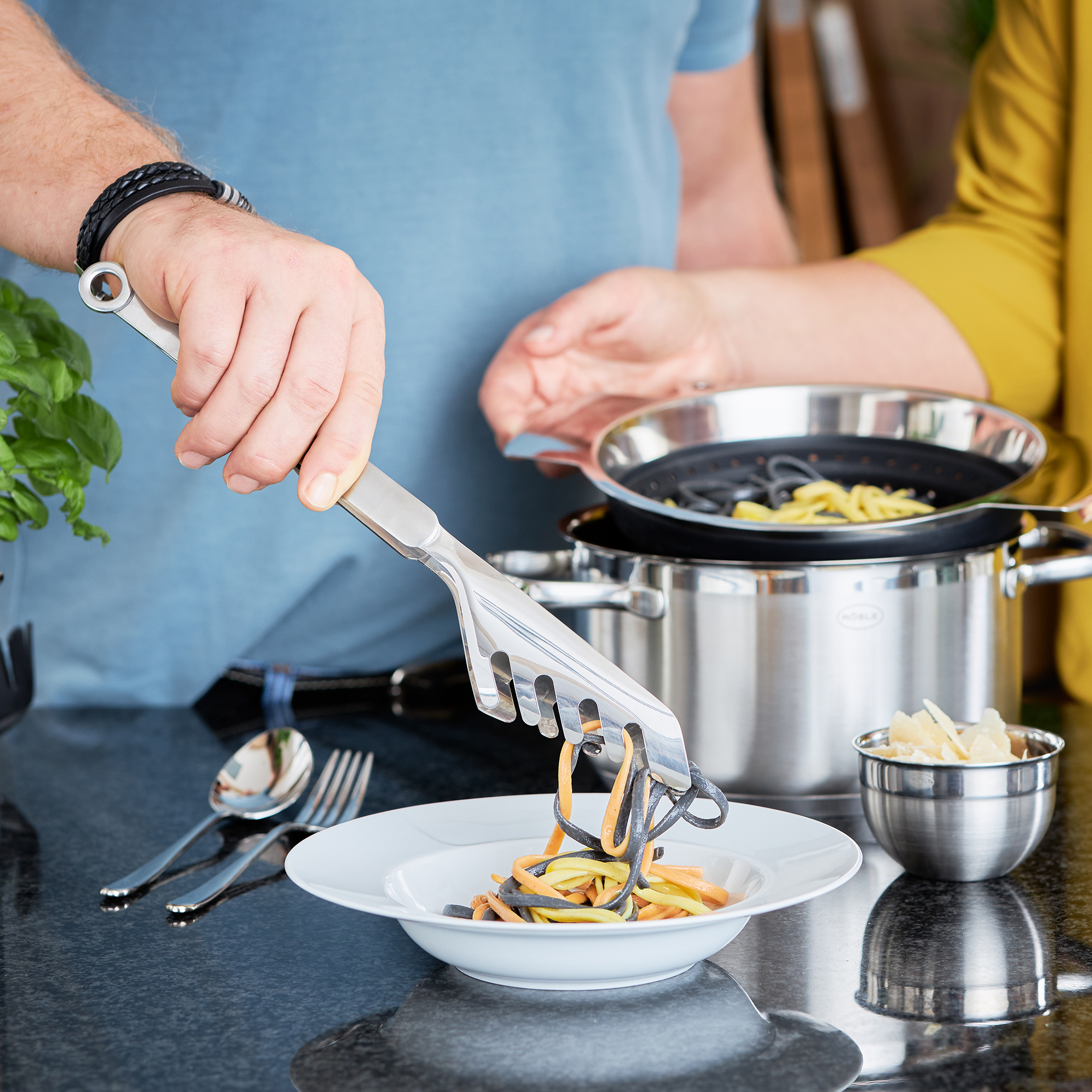 RÖSLE Spaghettizange in Aktion Spaghettizange aus Edelstahl, beim Servieren von Spaghetti auf einem Teller.