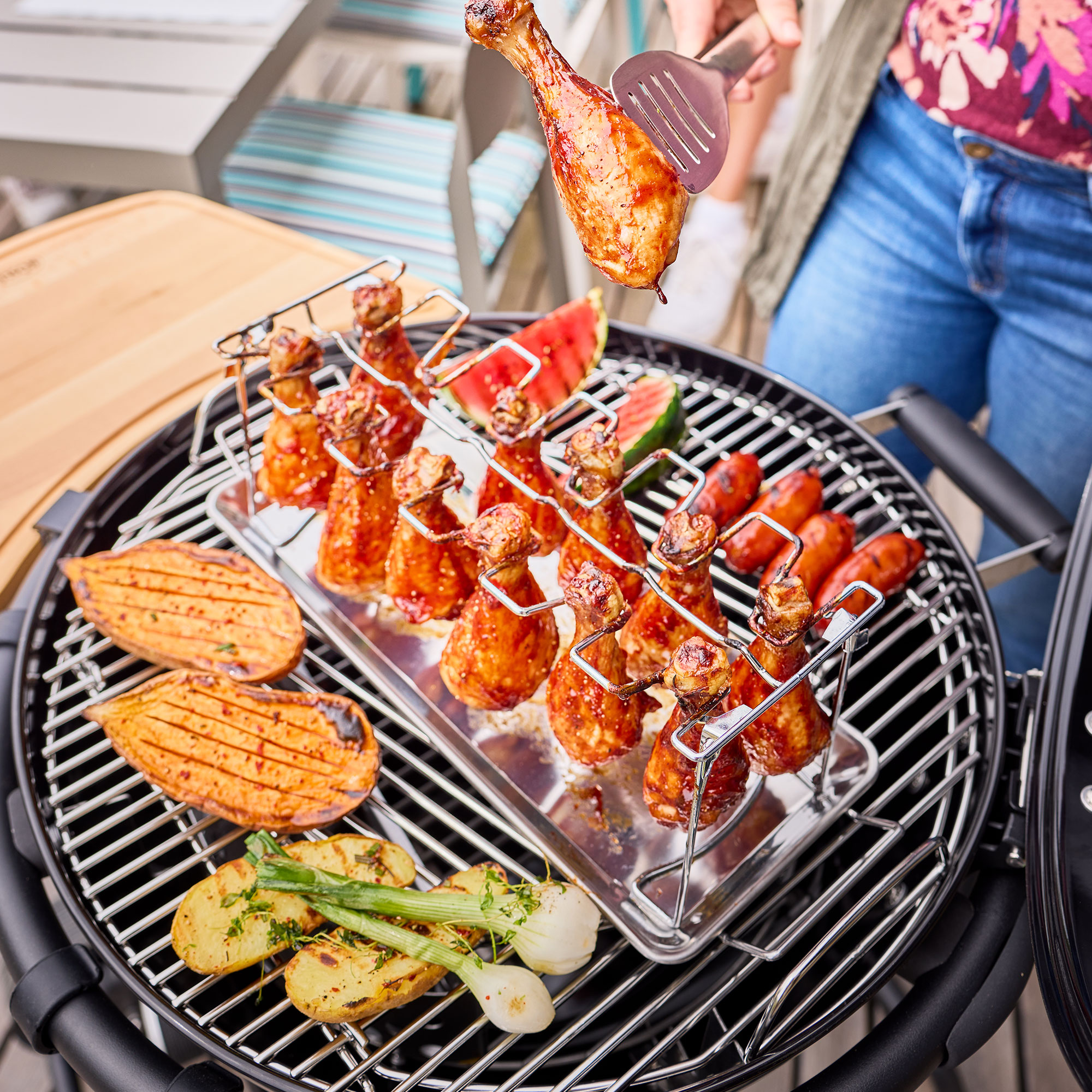 Grill mit Hähnchenschenkeln und Gemüse Holzkohlegrill mit Hähnchenschenkeln, Gemüse und Melonenstücken auf dem Grillrost.