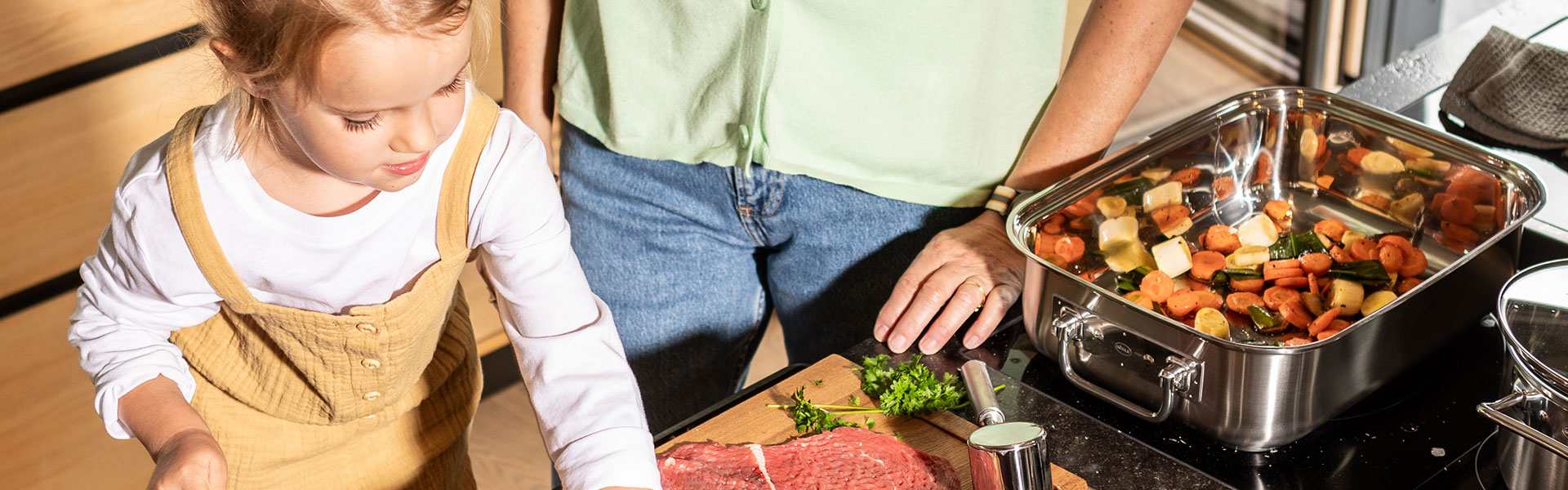 Gemeinsames Kochen in der modernen Küche Ein Kind und ein Erwachsener bereiten gemeinsam eine Mahlzeit in einer modernen Küche vor....
