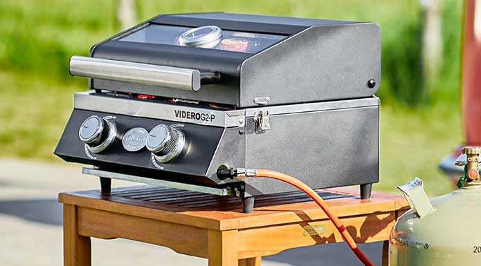 RÖSLE Gasgrill BBQ-Portable Videro G2-P Videro G2-P mit geschlossenem Deckel und Gasanschluss auf kleinem Tisch.