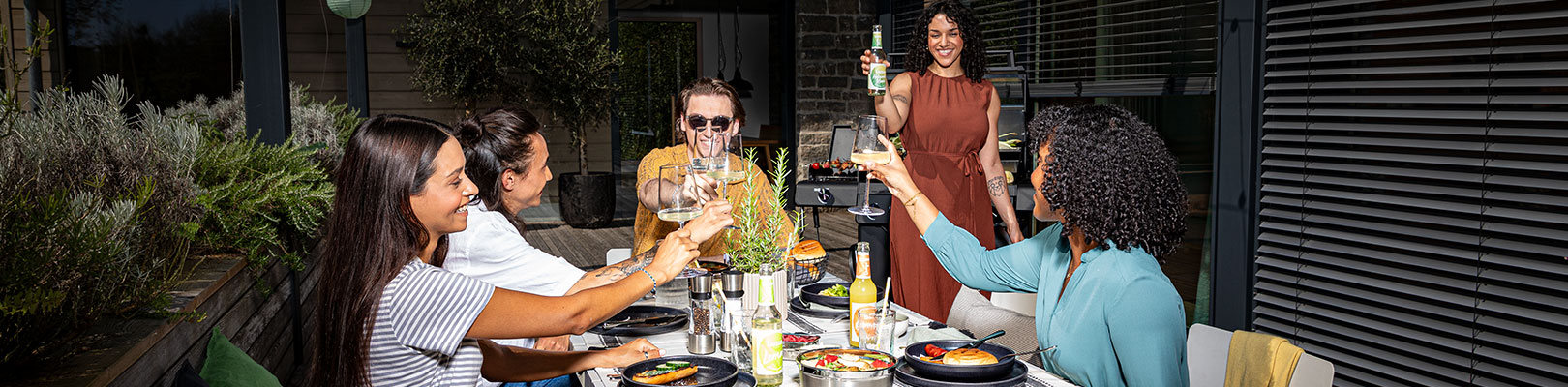 Allflame Freunde sitzen zusammen auf der Terrasse und stoßen an