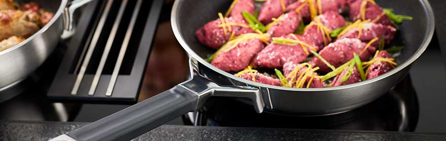 SILENCE PRO Silence Pro Pfanne mit lila gefüllten Teigtaschen und frischem Schnittlauch auf dem Herd.