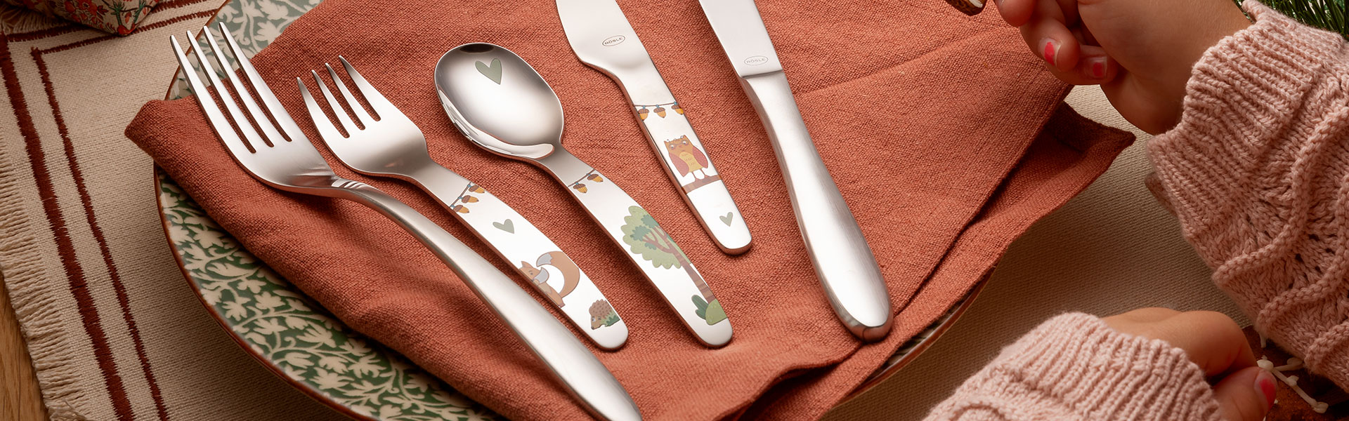 RÖSLE Besteckset auf Tisch Besteckset mit Gabel, Löffel, Messer und dekoriertem Dessertmesser auf einem rustikalen Tisch.