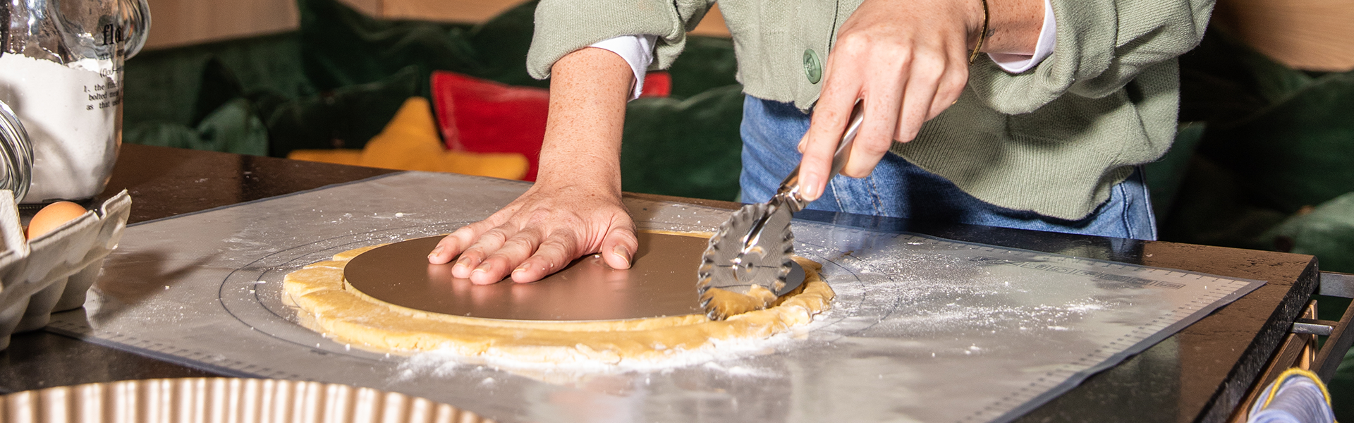 Backen Frau schneidet mit Teigrädchen einen Kreis aus einem Teig