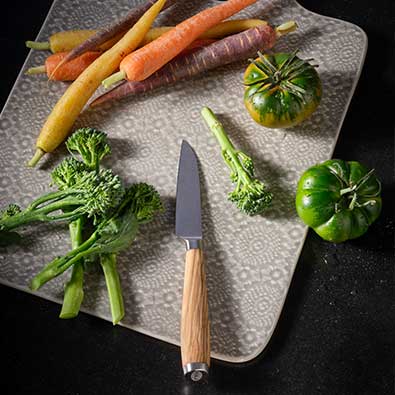 Vegetable knife series Artesano on cutting board with carrots and tomatoes.