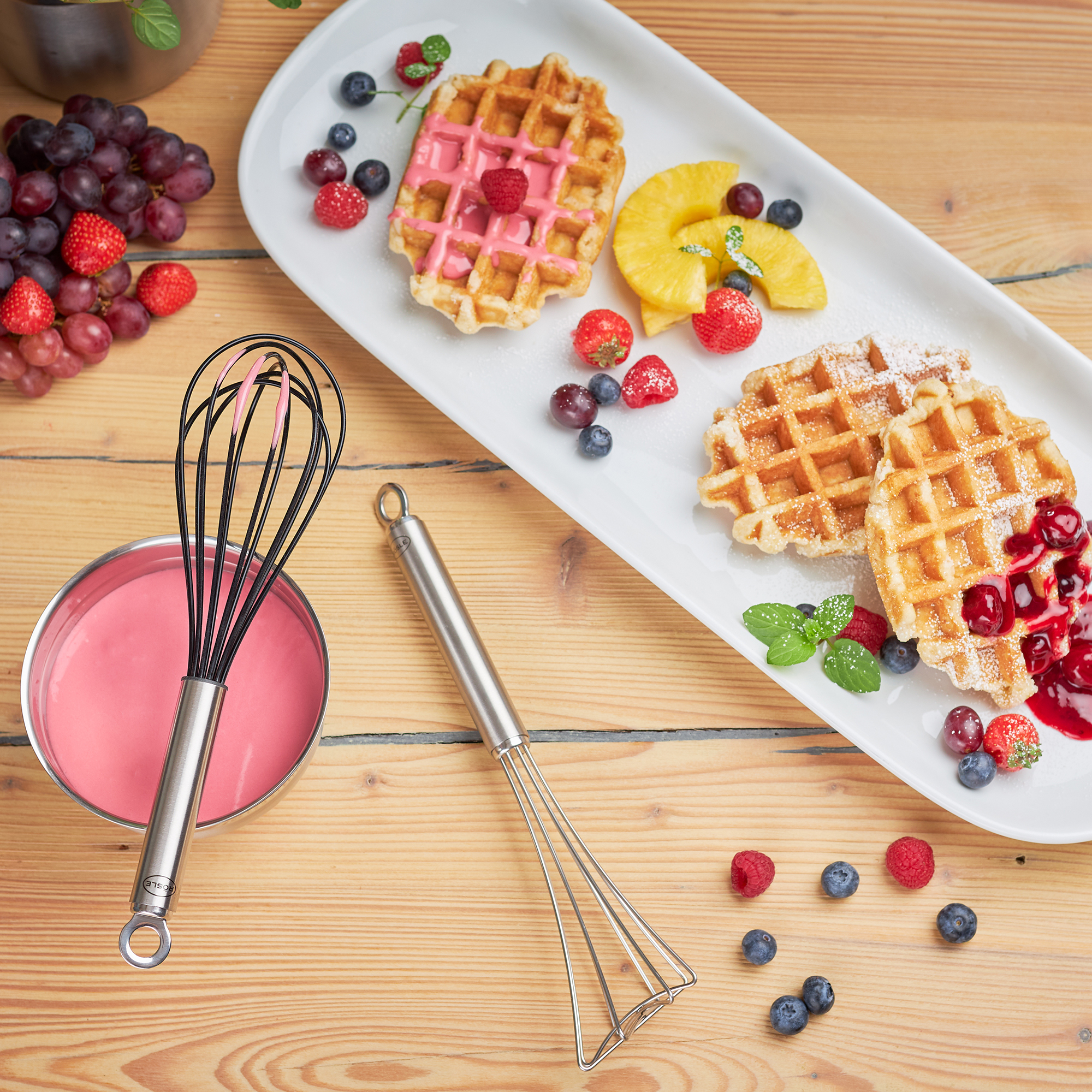 RÖSLE silicone whisk and waffles Silicone whisk, 22 cm, next to waffles and fruit on a table.