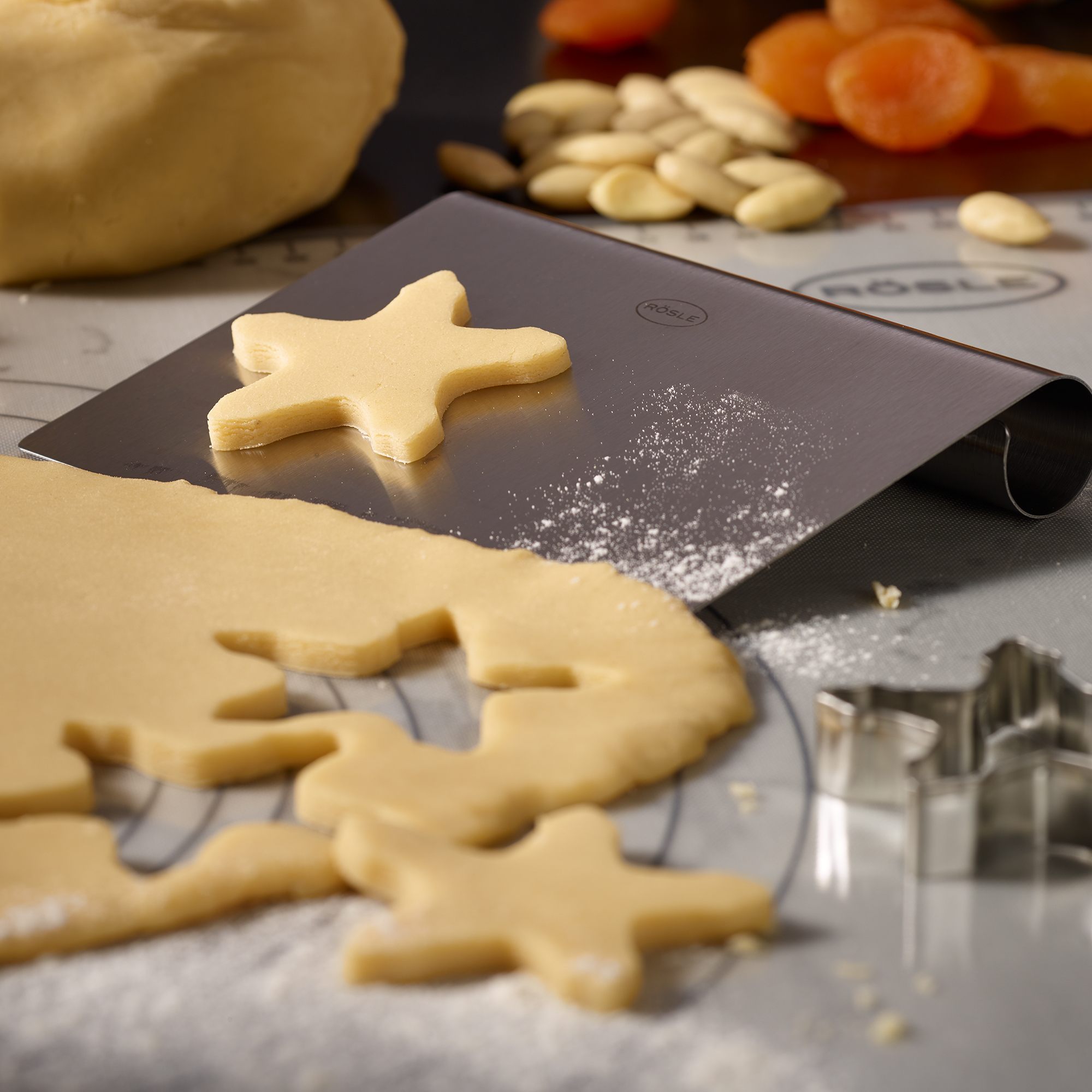 RÖSLE Silikon Back- und Arbeitsmatte Silikon Back- und Arbeitsmatte mit ausgerolltem Teig und Ausstechformen in Sternform.