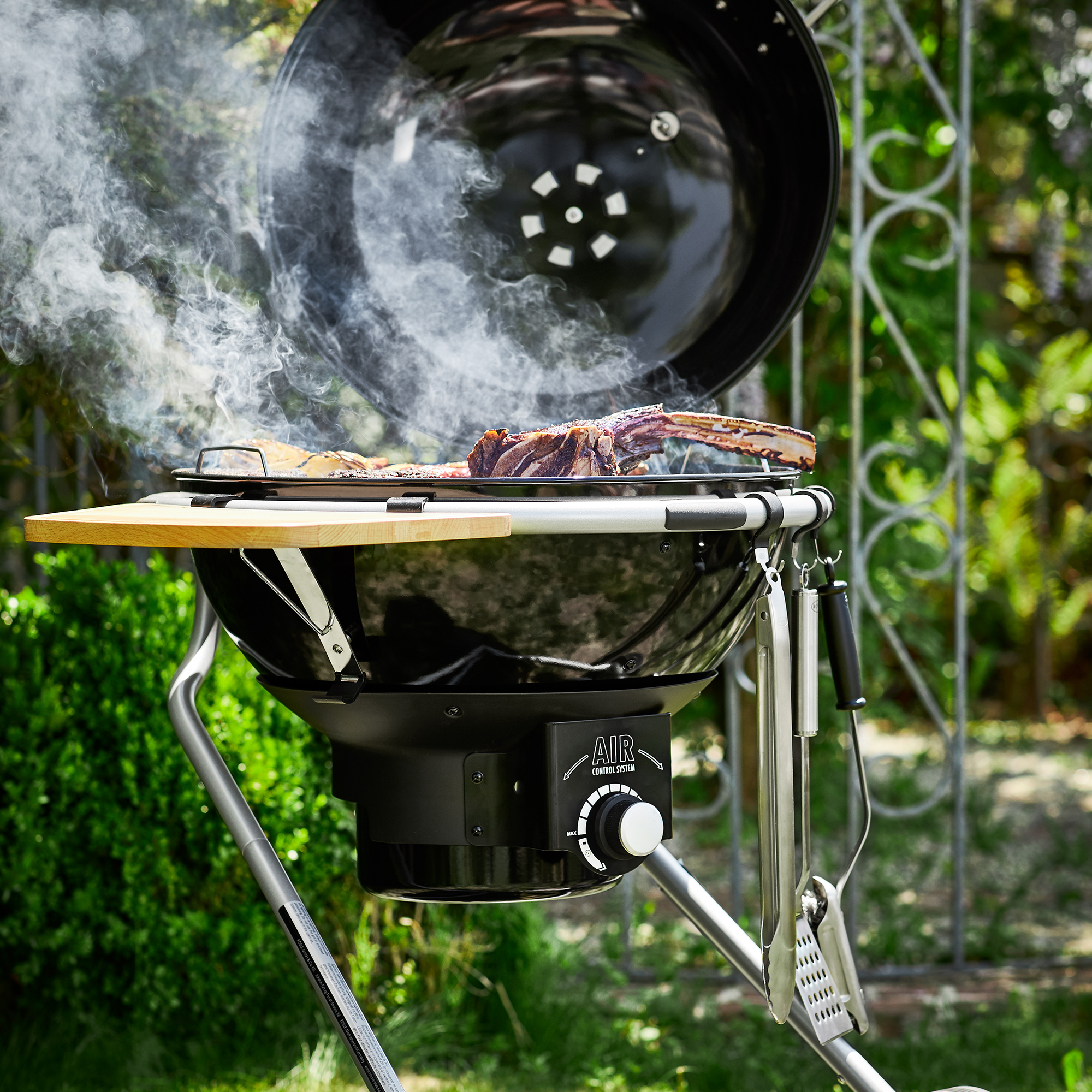 RÖSLE Grill mit Holzablage und Rauch Grill mit Holzablage, schwarzer Kessel, Rauchentwicklung, Fleisch auf dem Grillrost