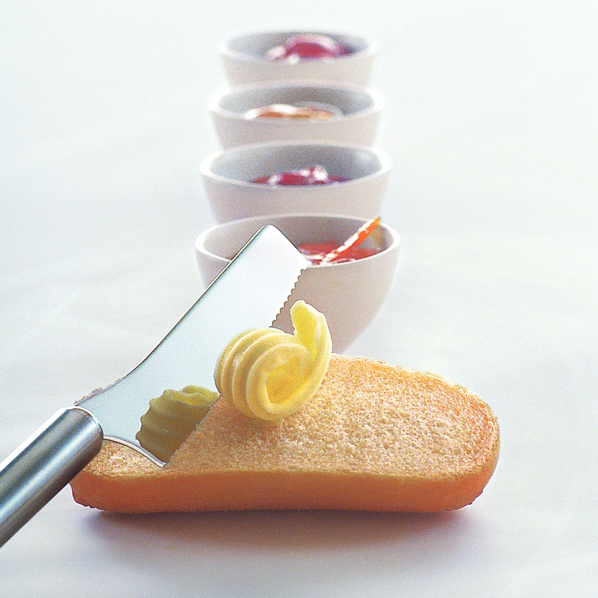 RÖSLE Frühstücksmesser Set Frühstücksmesser mit Butter auf einem Brötchen, im Hintergrund vier Schalen mit verschiedenen...