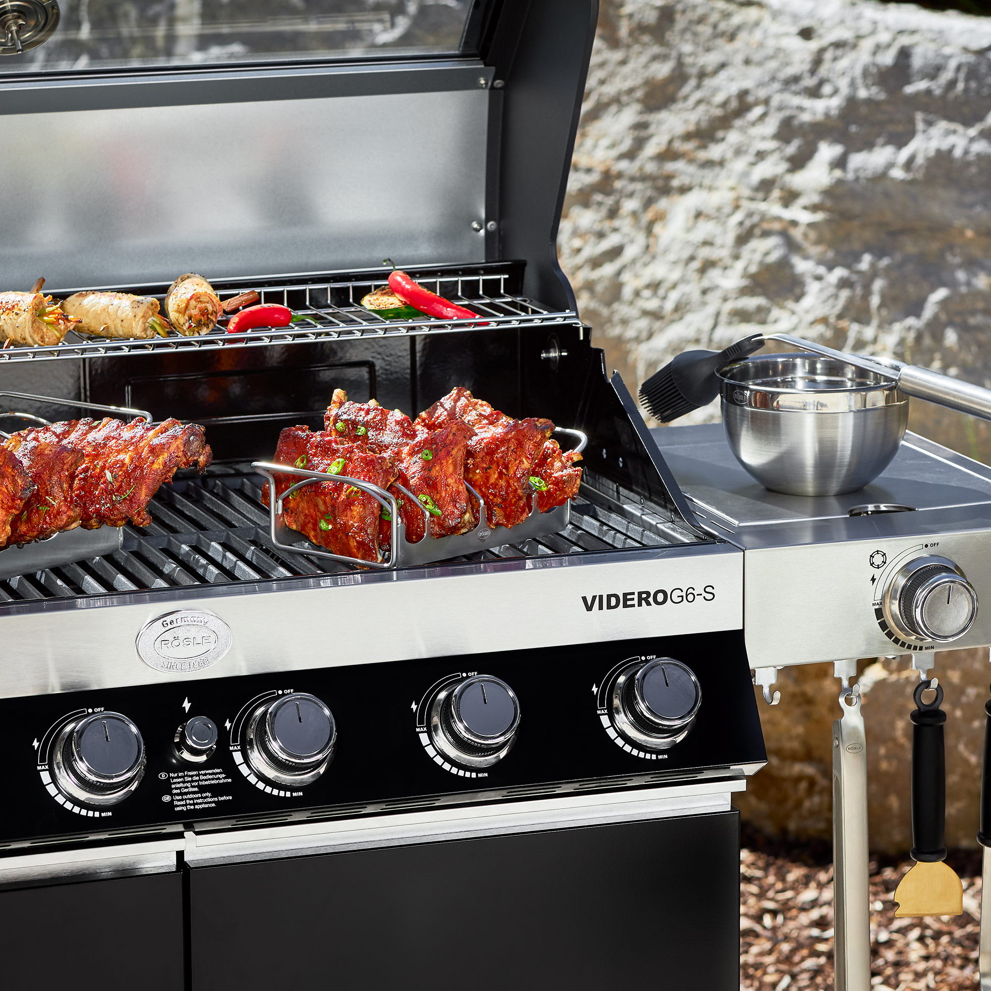RÖSLE VIDERO G6-S gas barbecue with rib rack VIDERO G6-S gas barbecue with rib holder, food and vegetables on the grill.