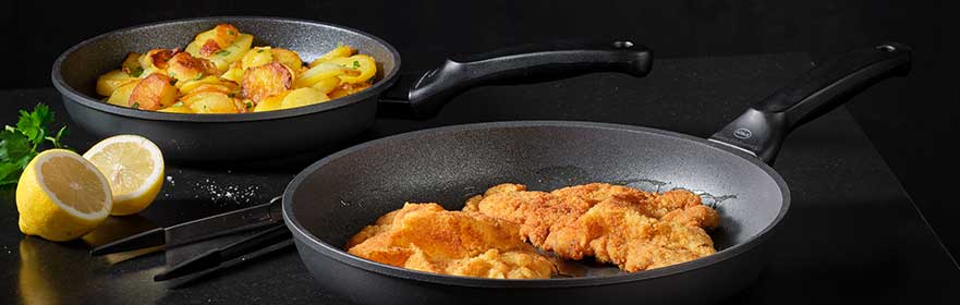 RÖSLE pannenset Pannenset met twee pannen, een met gebakken vis en de andere met aardappelen, beide met antiaanbaklaag.
