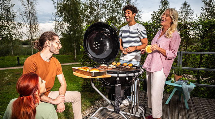 Kugelgrill AIR F60 Vier Freunde stehen um den Grill und lachen zusammen.