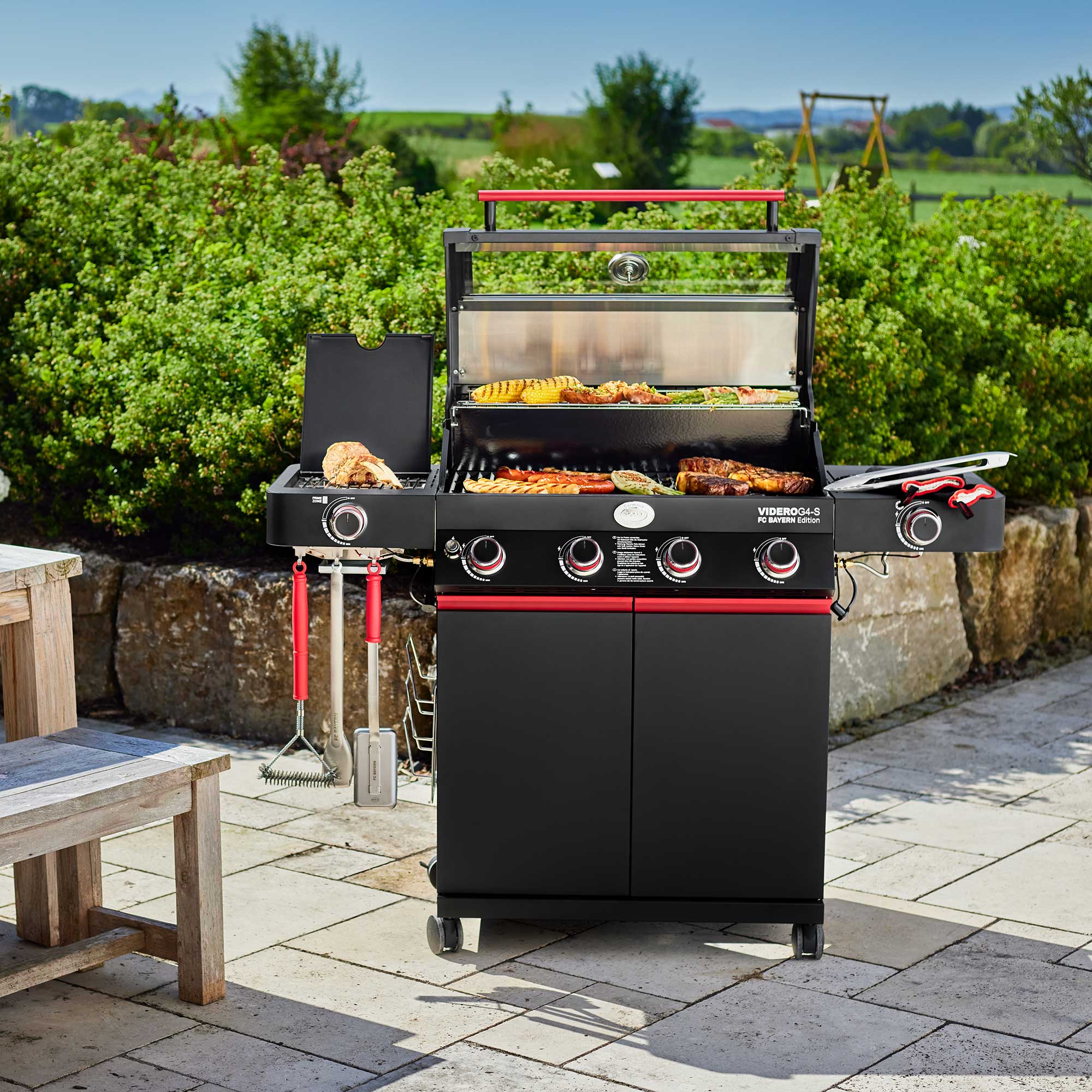 Gasgrill Videro G3-S in der FC Bayern Edition, schwarz mit rotem Akzent, auf einer Terrasse...