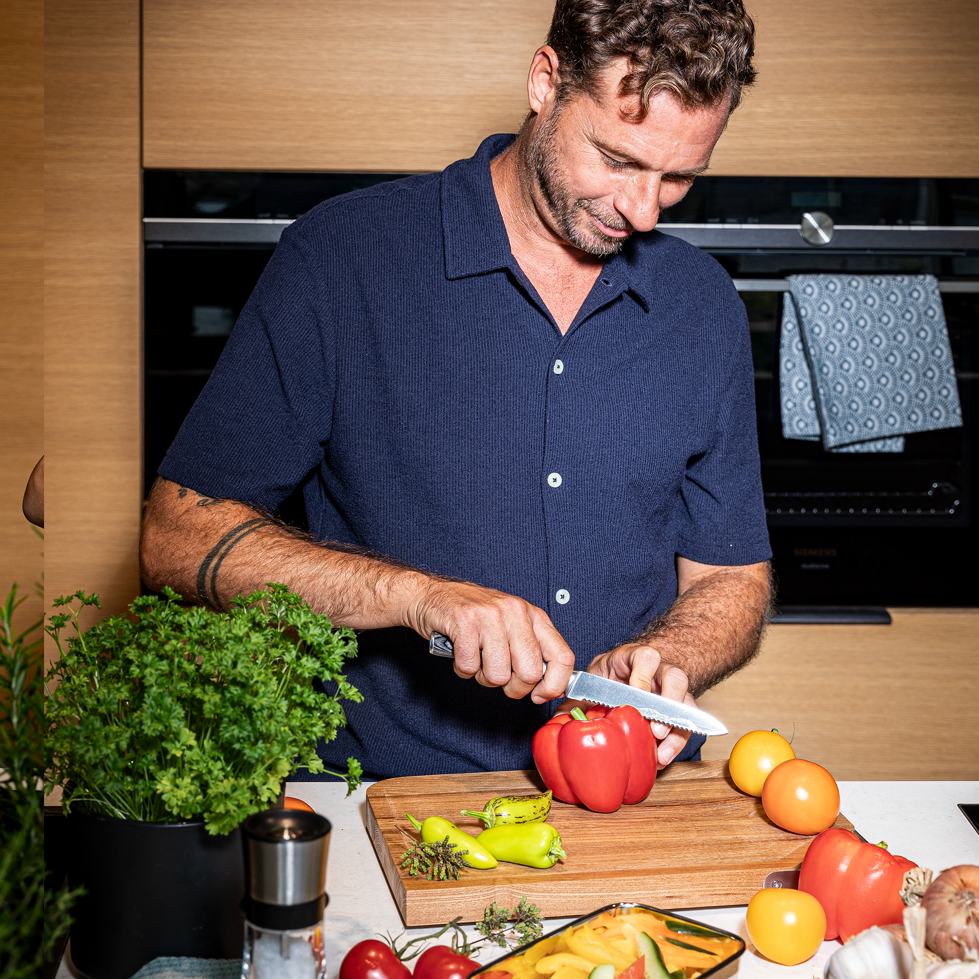 Mann mit RÖSLE Universalmesser in der Küche Mann schneidet eine rote Paprika mit einem Universalmesser auf einem Holzbrett in einer modernen...