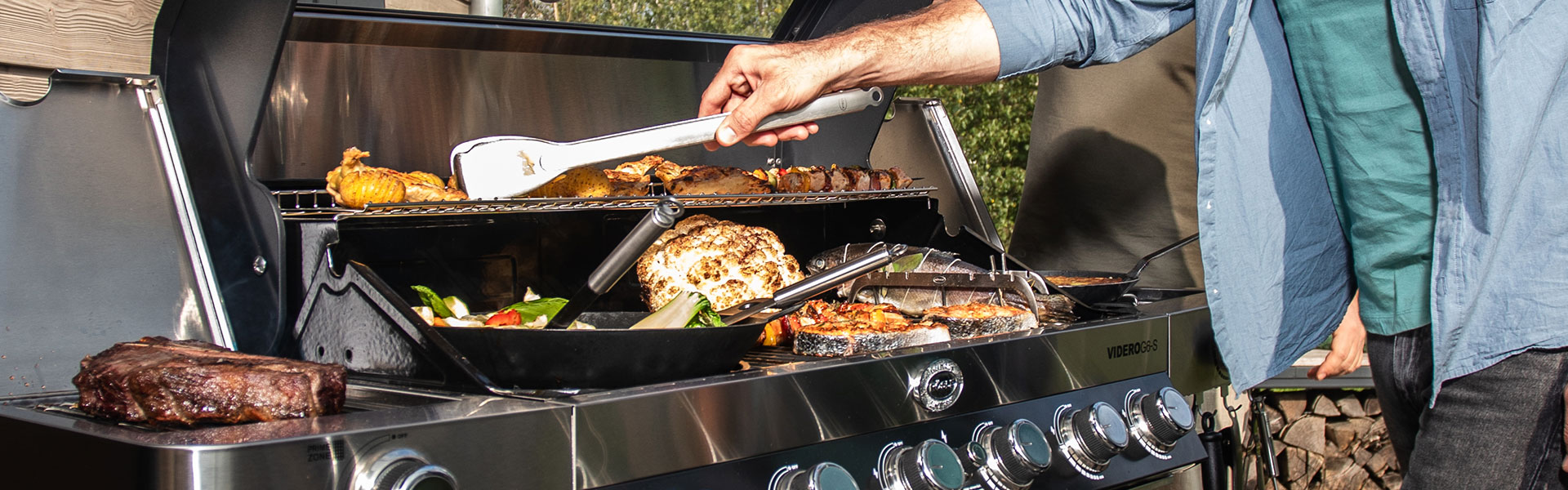 Mann benutzt RÖSLE Grillbesteck Grillbesteck in Aktion, während ein Mann mit einer Zange Grillgut auf einem modernen Grill...