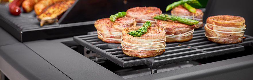 Grill rek met gerechten zoals gevulde bacon en asperges, op een grill.