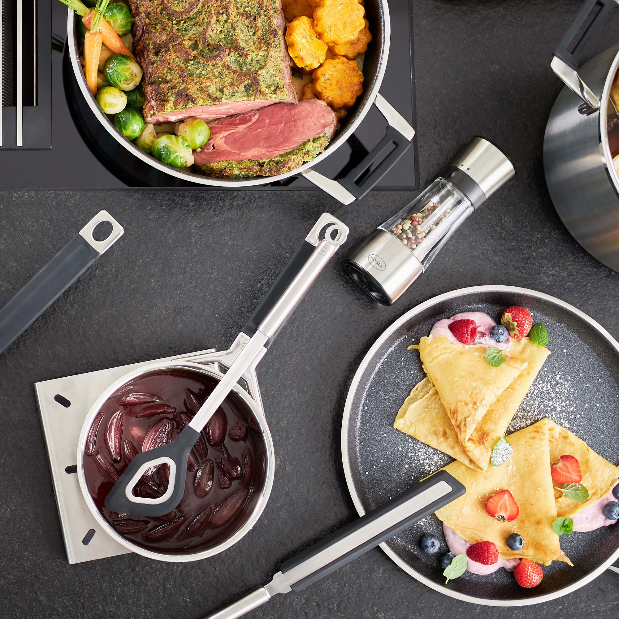 RÖSLE round handle silicone cooking spoon with hole Round-handled silicone cooking spoon surrounded by various cooking utensils and dishes.