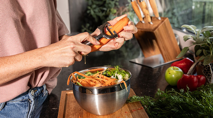 Gemüse Frau schält mit Pendelschäler Karotten