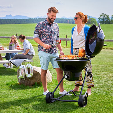 Two friends are standing at the grill and grilling together.