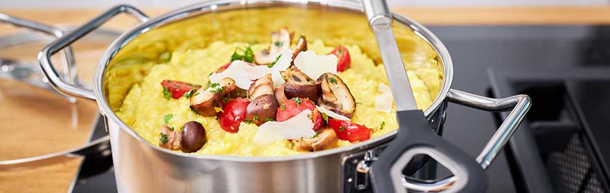 RÖSLE Kochtopf mit Gemüse Kochtopf aus Edelstahl mit Gemüse und Kräutern auf einem Herd.