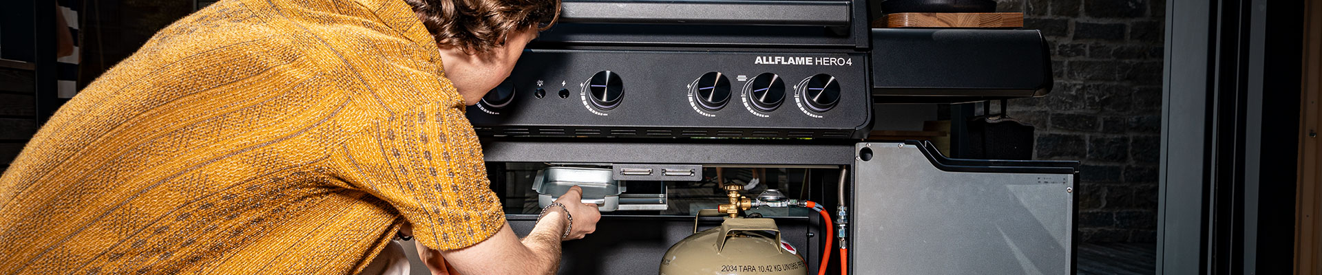 Fehlersuche Gasgrill. Mann holt Fettauffangwanne aus dem ALLFLAME Grill heraus