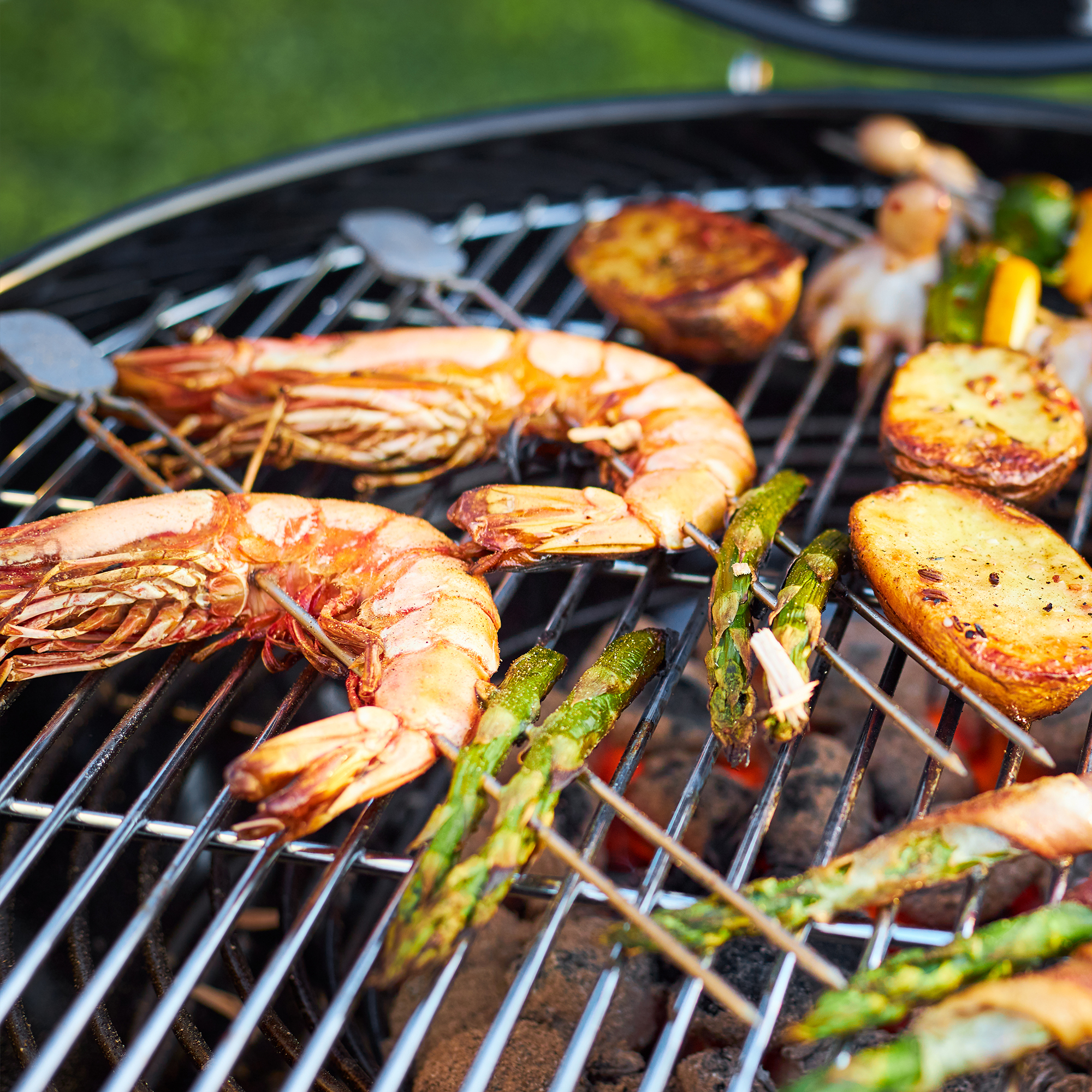 Grill skewers with seafood and vegetables Grill skewers with prawns, asparagus and potatoes on a grill rack.