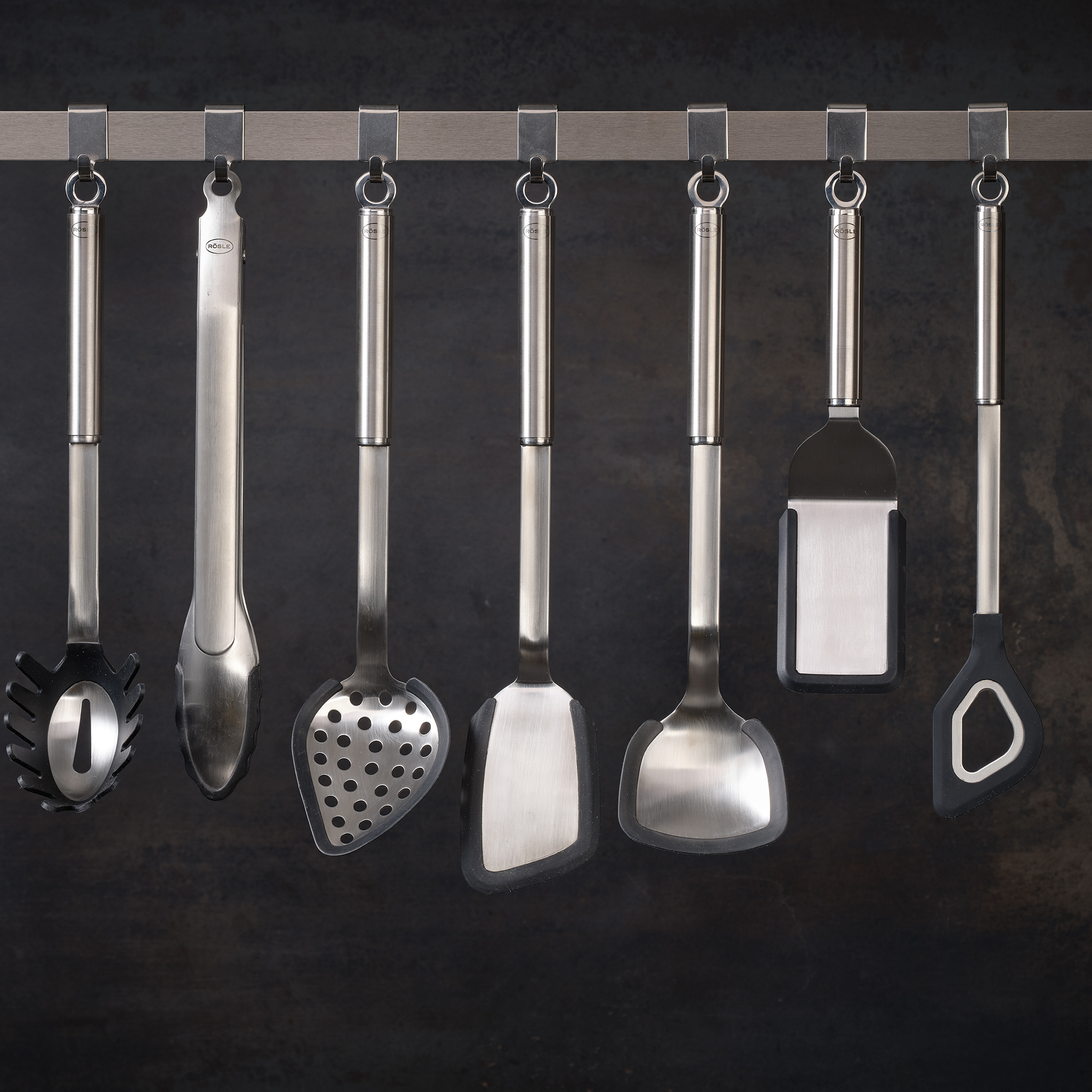 Cooking utensils from RÖSLE Stainless steel and silicone cooking utensils, including cooking spoon with hole, on a hanger.
