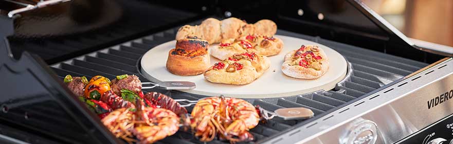 RÖSLE Videro Grill mit Grillzubehör Videro Grill mit verschiedenen Grillzubehörteilen, darunter Pizzastein, Garnelen, Gemüse und...
