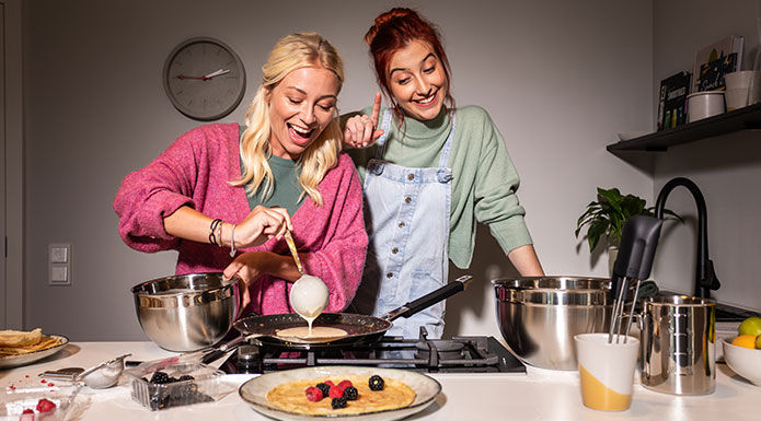 Crepes Two friends are making crepes together. Woman pouring batter into the pan