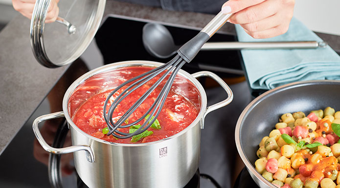 Schneebesen rührt Tomatensuppe im Topf um