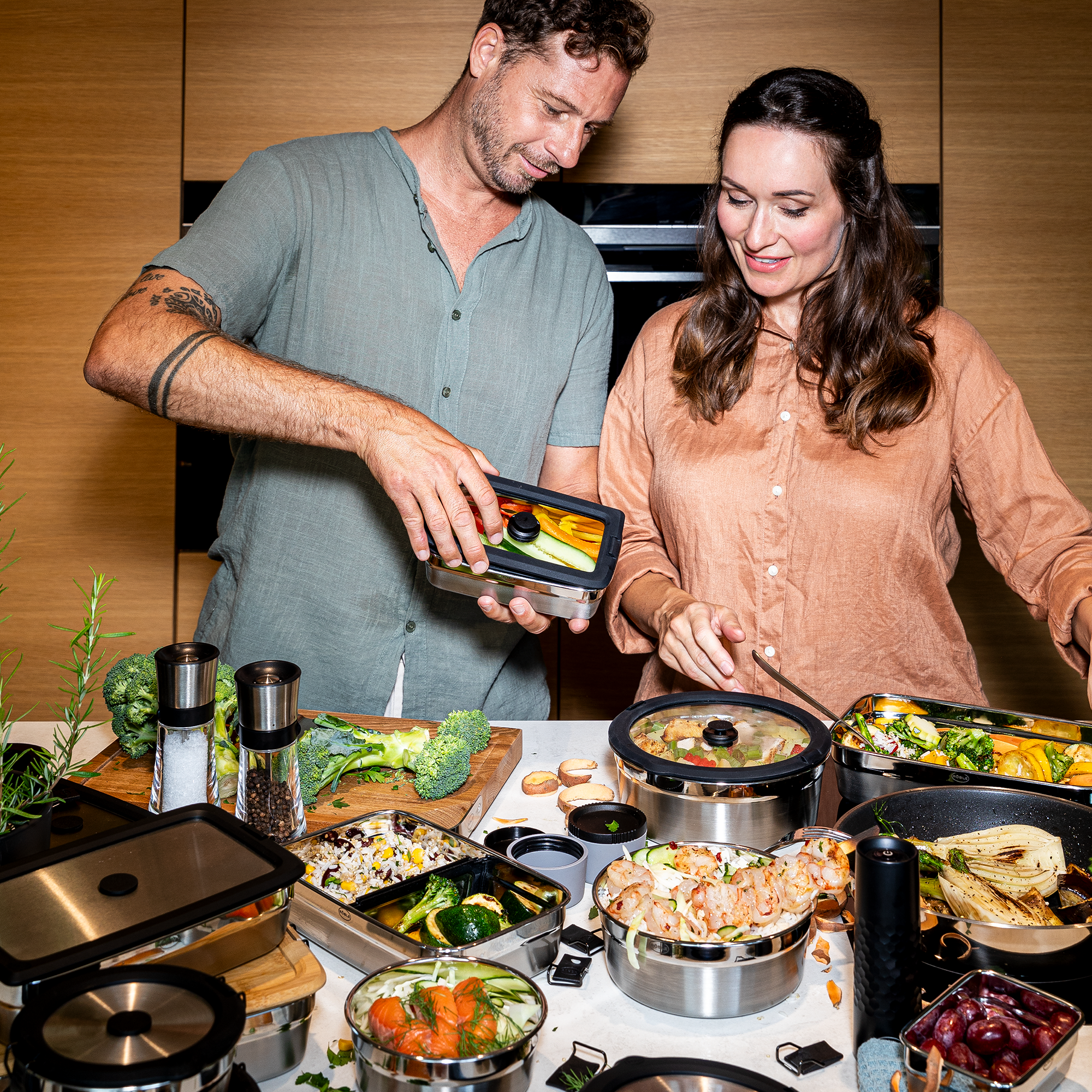 Zwei Personen mit RÖSLE Flexx2go Behältern beim Kochen Flexx2go 1,0l Behälter in Benutzung, zwei Personen bereiten Essen vor, umgeben von verschiedenen...